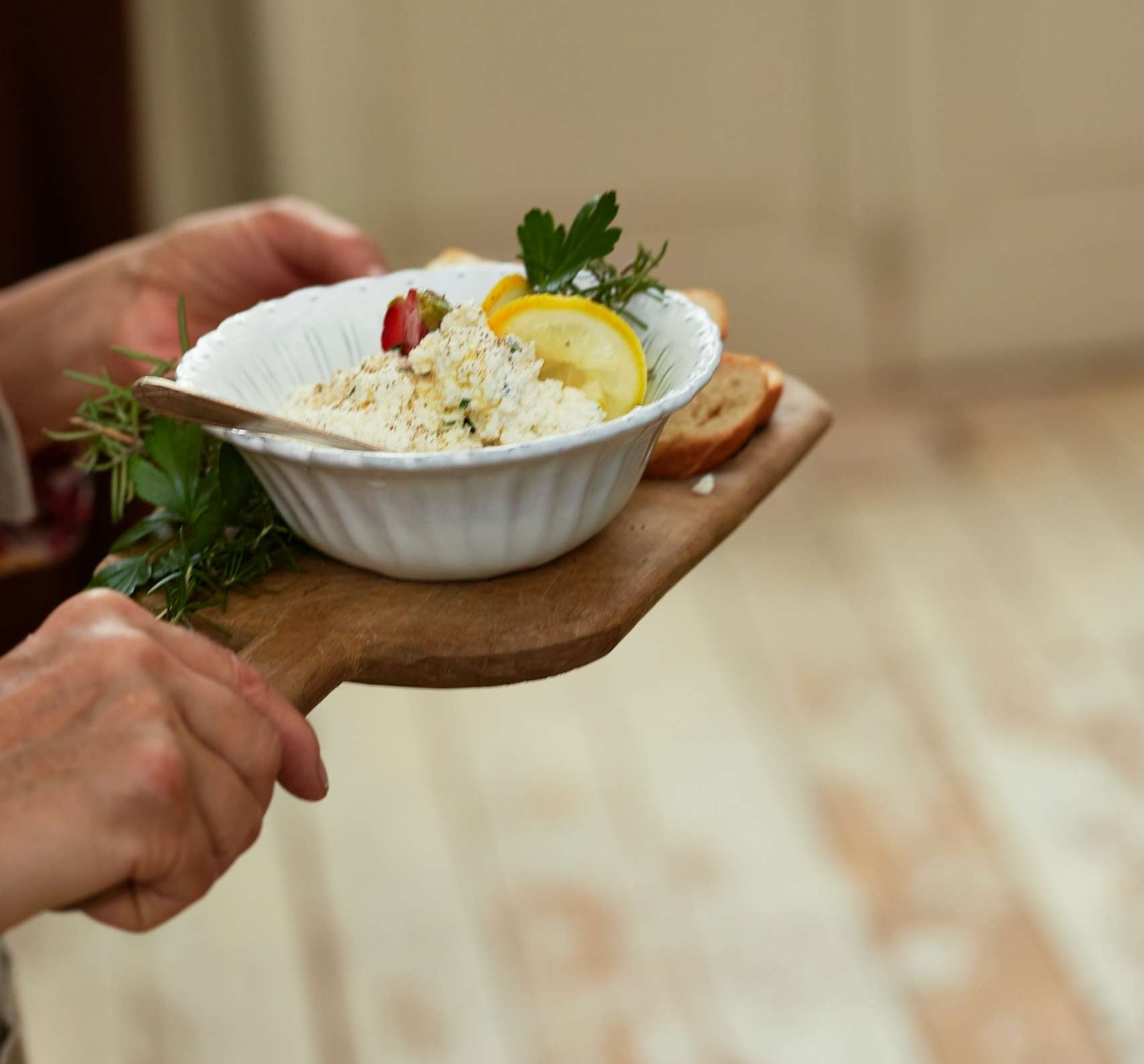 A person holding a bowl of food on a wooden board